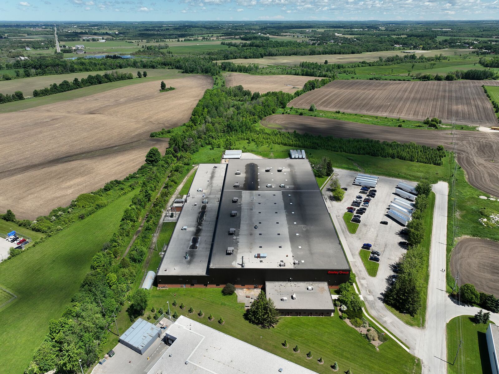 High aerial view of a manufacturing facility set in a patchwork of ploughed and planted fields