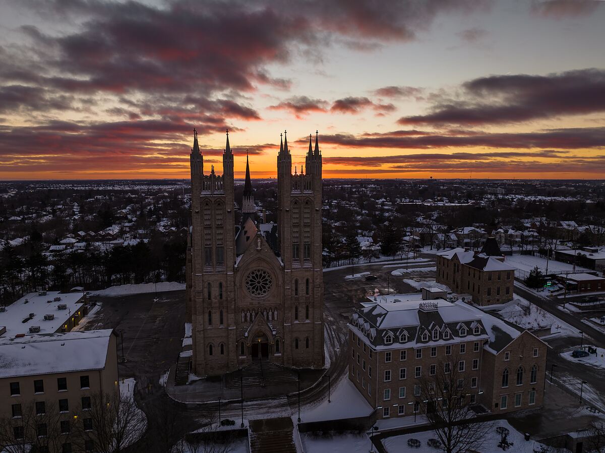 Aerial view of the Basilica of Our Lady Immaculate in Guelph at winter sunset, its twin spires rising above the snow-covered downtown