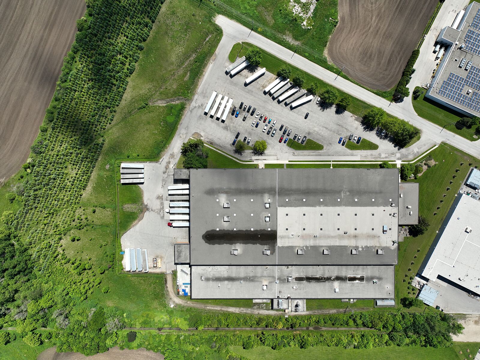Straight-down aerial view of a factory roof, showing rooftop units, seams and the adjoining trailer yard