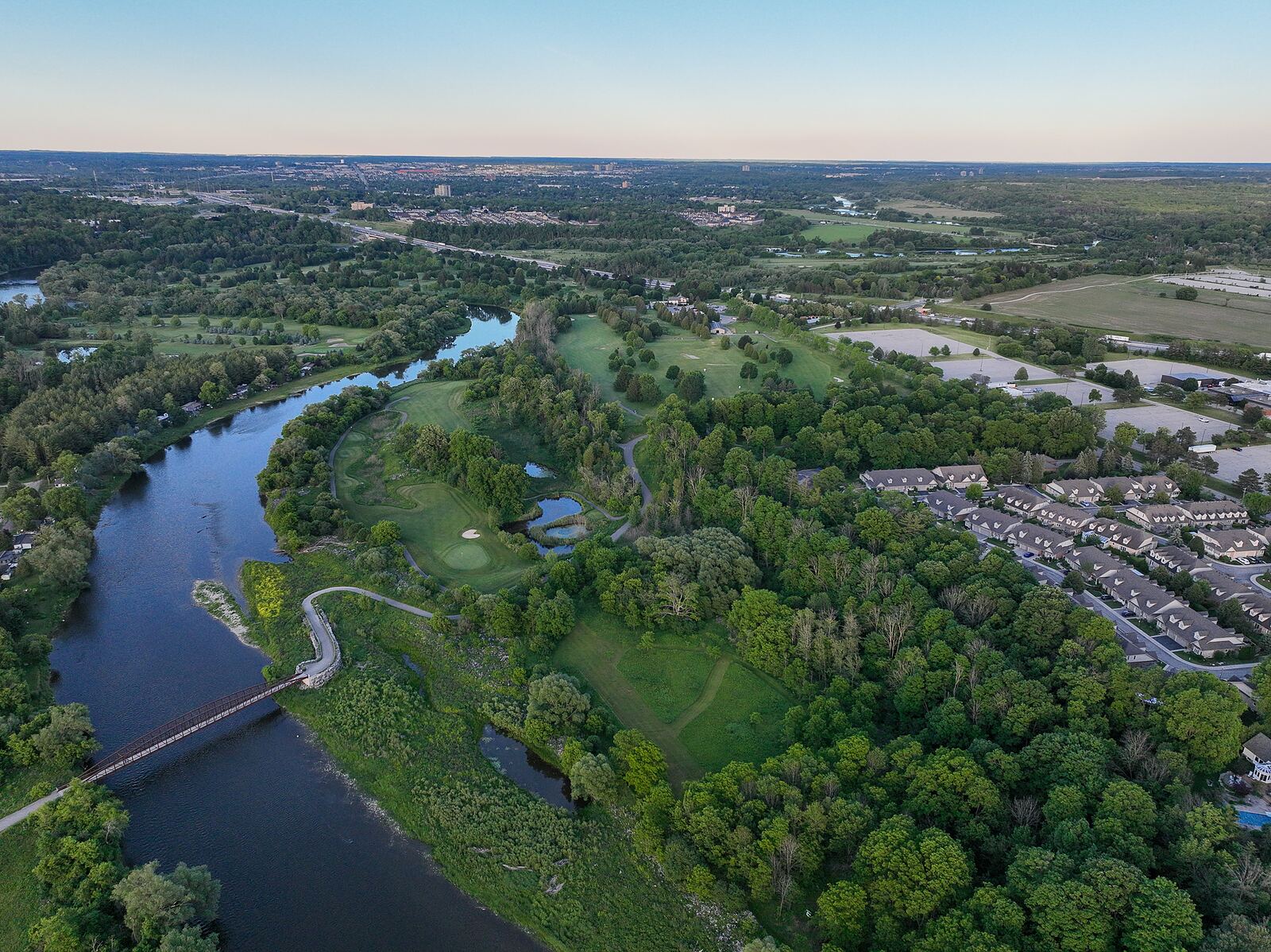 Aerial view of a bend in the Grand River with a pedestrian footbridge, floodplain and trail network